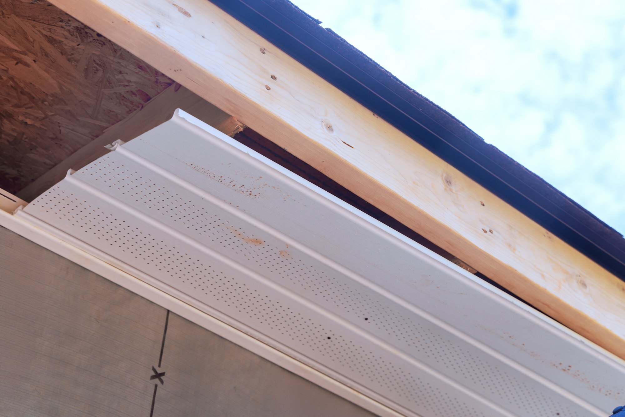 Worker installation of upvc soffit boards on roof corners ceiling rafters a house